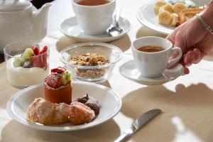 a table with plates of pastries and cups of coffee at Park Hotel Chianti in Tavarnelle in Val di Pesa