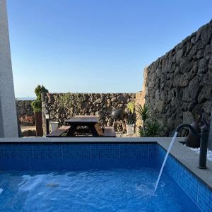 a swimming pool with a fountain in front of a stone wall at Nolgureum private pool villa in Jeju