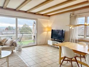 a living room with a table and a tv at Horizon Lac - wifi - parking in Morges