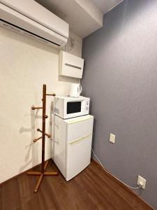 a kitchen with a microwave on top of a refrigerator at Small hidden wooden house in Osaka