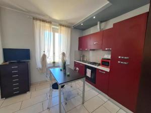 a kitchen with red cabinets and a table in it at Appartamento Valentina in Cremona