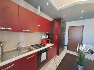 a kitchen with red cabinets and a stove and a sink at Appartamento Valentina in Cremona