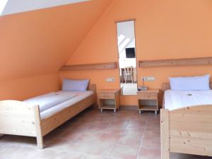 twee bedden in een kamer met oranje muren en een spiegel bij Landgasthof Asum in Dasing