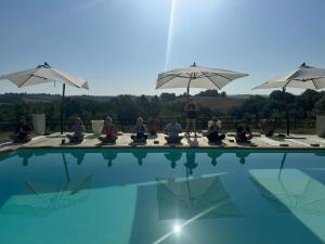 a group of people sitting around a pool with umbrellas at Pure Gardères in Monlezun