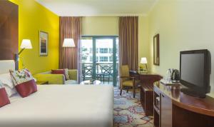 a hotel room with a bed and a desk and a television at Coral Dubai Deira Hotel in Dubai