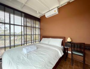 a bedroom with a bed and a large window at Sunset House Khao Yai in Pak Chong