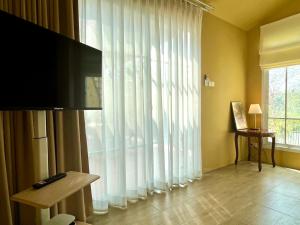 a living room with a large window with white curtains at Sunset House Khao Yai in Pak Chong