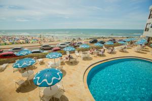 an overhead view of a pool with umbrellas and a beach at Dunas Praia Hotel in Torres