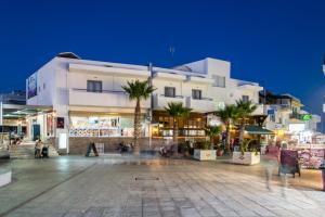 a large white building with palm trees in front of it at Rio Hotel in Kardamaina
