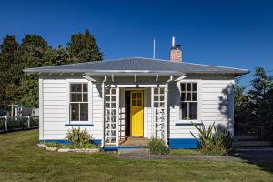 a small white house with a yellow door in a yard at Ohakune's Yellow Door in Ohakune