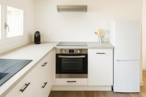 a white kitchen with a stove and a refrigerator at Appartement modulable in Lannemezan