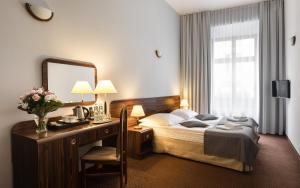 a hotel room with a bed and a desk with a mirror at Hotel Wit Stwosz in Krakow