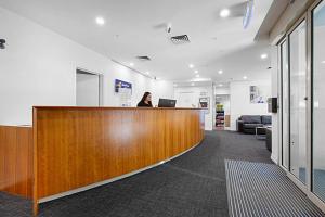 a woman sitting at a reception desk in an office at Comfort Apartments Melbourne Central in Melbourne