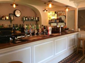 a bar with a counter and a clock on the wall at Three-Cranes in Turvey