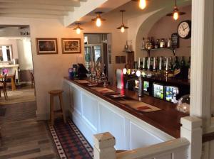 a bar in a restaurant with a clock on the wall at Three-Cranes in Turvey