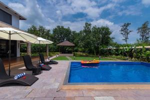 a swimming pool with chairs and an inflatable at Classique Woods by StayVista with Lawn with Gazebo & Bar, Indoor Fun in Karjat +38 photos