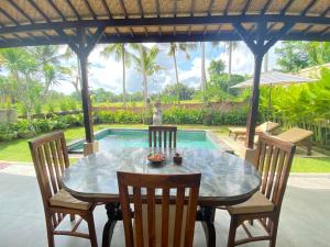 a dining room table with chairs and a pool at Shima House in Sukawati