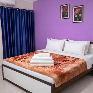 a bedroom with a large bed with purple walls at Hotel Aryaman in Haridwār +3 photos