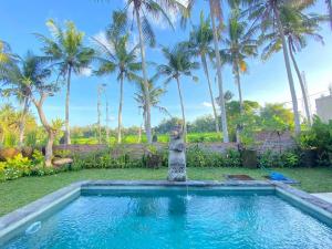 a swimming pool with a fountain in a yard with palm trees at Shima House in Sukawati +1 photo