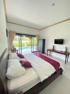 a large bed with pillows and a television in a bedroom at Shima House in Sukawati