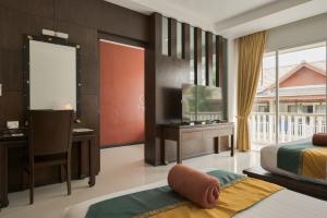 a bedroom with two beds and a desk and a television at Baan Karonburi Resort in Karon Beach