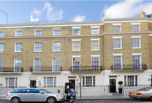 a large brick building with cars parked in front of it at Astors Belgravia in London