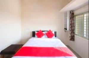 a bedroom with a large bed with red pillows at SLP Residency in Mysore +1 photo
