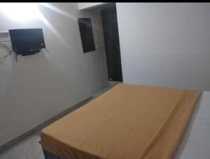 a room with a bed and a tv on a wall at SLP Residency in Mysore