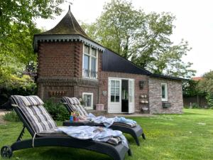 two chairs sitting in front of a brick house at Petit Château luxe vakantiehuis, prive hottub en zwembad in Heythuysen