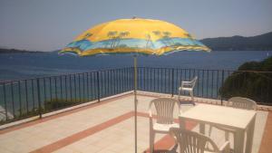 a table and chairs on a balcony with an umbrella at Holiday Home Smokvica in Viganj