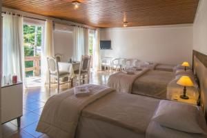 ein Hotelzimmer mit 3 Betten sowie einem Tisch und Stühlen in der Unterkunft Pousada do Tirol in Gramado
