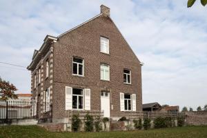 a brick house with white windows and a fence at De Oude Pastorij in Maarkedal
