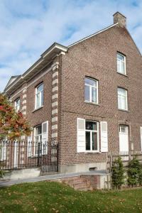 um edifício de tijolos com janelas brancas e uma cerca em De Oude Pastorij em Maarkedal