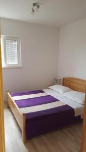 a bedroom with a large bed with purple sheets at Apartment Marta in Podgora