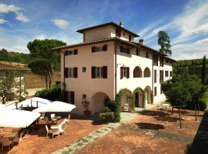 un grand bâtiment blanc avec des tables et des parasols dans l'établissement Appartamenti Agriturismo La Canonica, à Certaldo