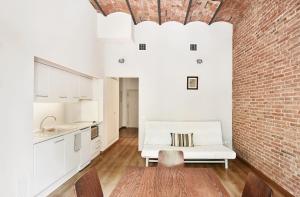 バルセロナにあるMayerling Schumann Barcelonaの白いソファとレンガの壁が備わるリビングルーム