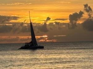 a sail boat in the ocean with a sunset at Villa Paradiso in Basseterre