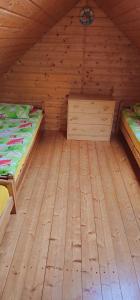 a room with two beds and a wooden floor at Rybacka chata in Rusinowo