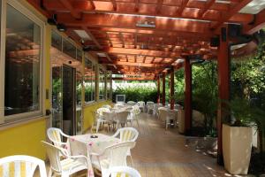 a patio with white tables and white chairs on it at Hotel Metron in Cesenatico