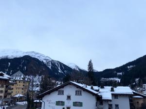 a snow covered mountain in the distance with a white building at Hotel Alpenblick in Klosters