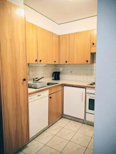 a kitchen with white appliances and wooden cabinets at Centre Thermal studio NORD S4003 in Ovronnaz