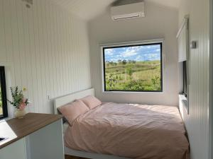 a small bedroom with a bed and a window at The tiny homes at The Original Farm in Yass