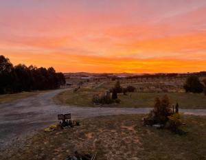 an empty road with a sunset in the background at The tiny homes at The Original Farm in Yass