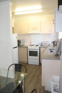 a kitchen with white appliances and a glass table at The Sundown Stay in Dubbo