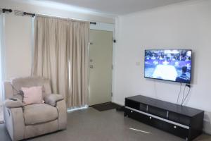 a living room with a chair and a flat screen tv at The Sundown Stay in Dubbo