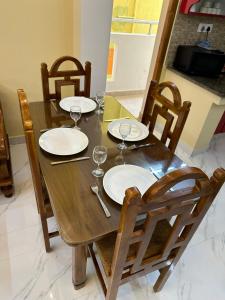 a wooden table with plates and wine glasses on it at Sri Apartment Homestay 2BHK Pondicherry A1 in Pondicherry +11 photos
