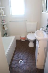 a bathroom with a toilet and a tub and a sink at The Sundown Stay in Dubbo +4 photos