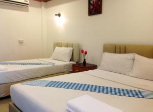 two beds in a room with red flowers on a table at Parada Place in Khon Kaen