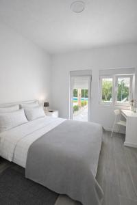 a white bedroom with a large bed and a desk at Casa Silva Diamond in Pinhal Novo