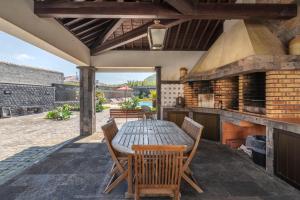 an outdoor kitchen with a wooden table and chairs at Heated Saltwater Pool-Private Beachside Oasis in Mosteiros